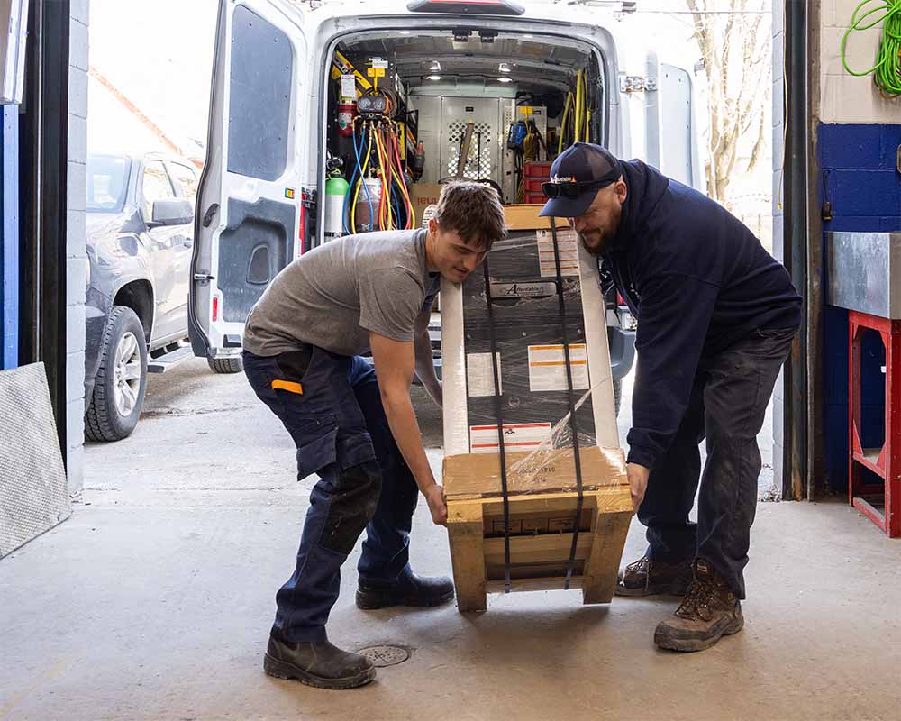 Two furnace installers load a brand new furnace from Affordable Heating and Cooling into a work van, ready for a fast professional installation.